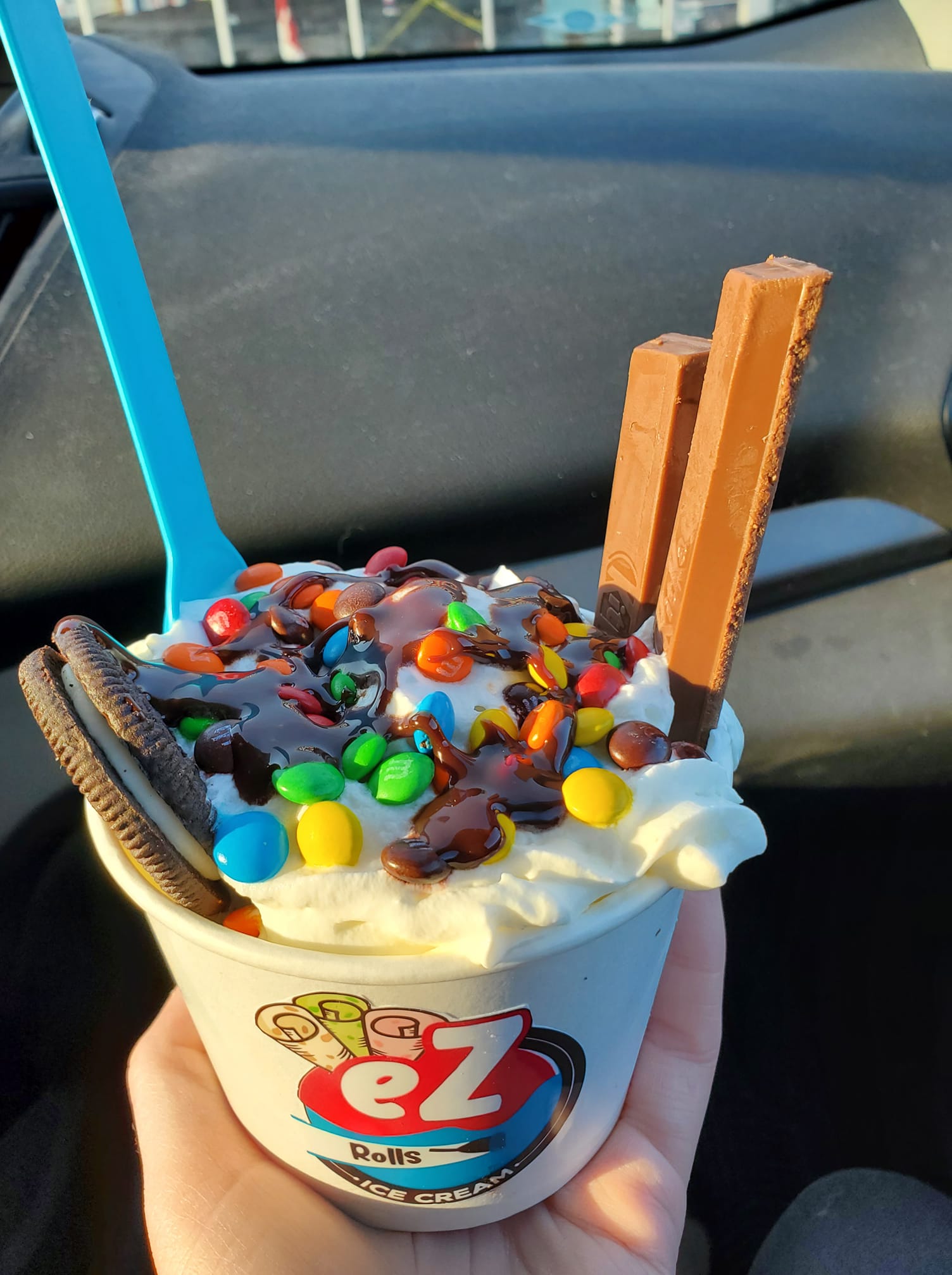 Loaded ice cream cup with M&Ms, Oreo cookie, wafer sticks, and chocolate sauce